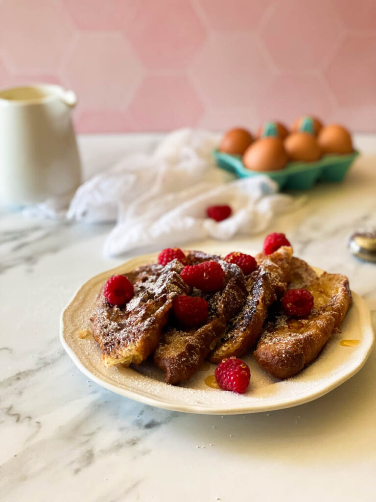  croissant pain perdu with raspberries, in the back, eggs, towel and milk jug