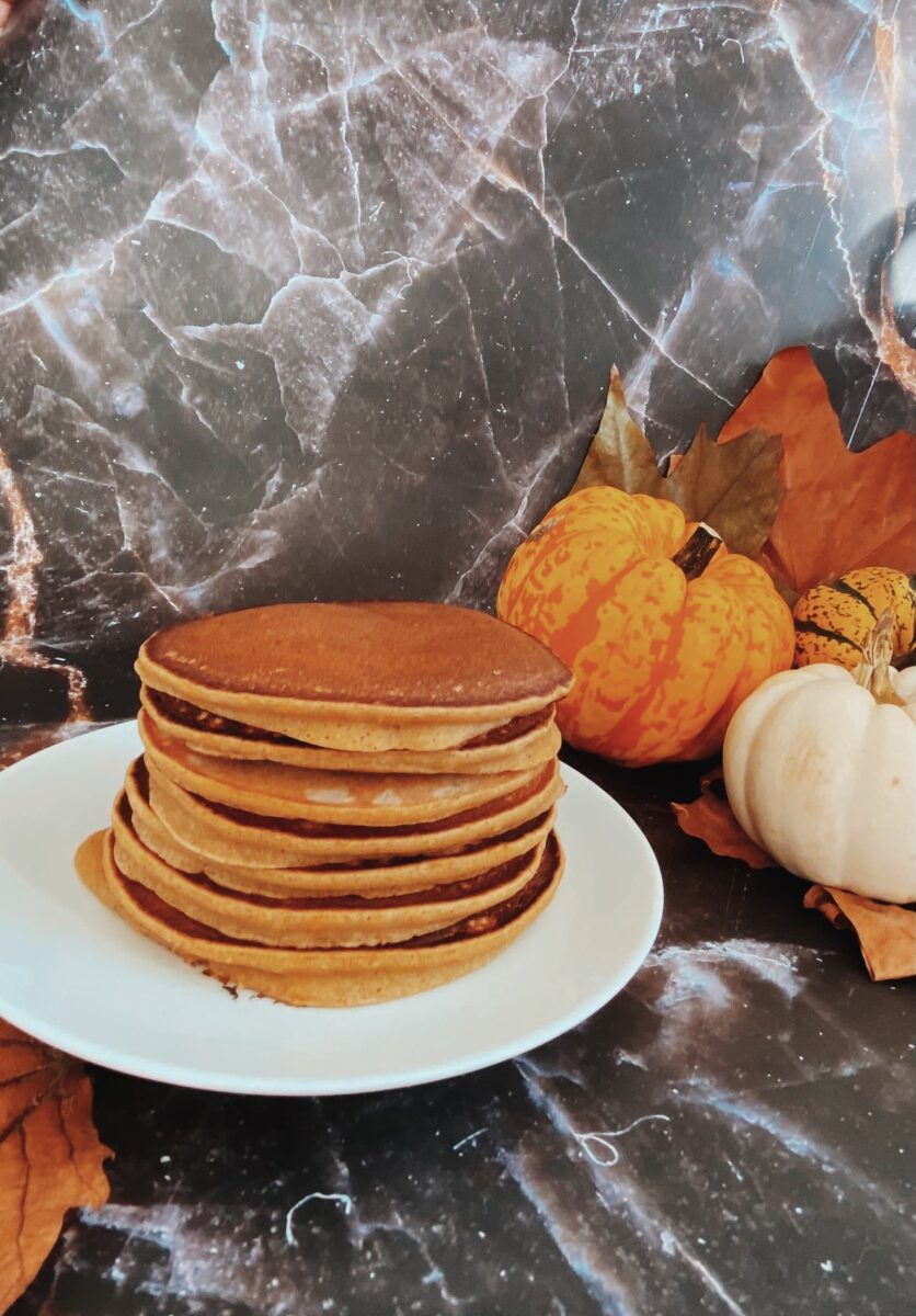 pumpkin pie spice pancakes on a plate, pumpkin and leaves on the side, on a black marble