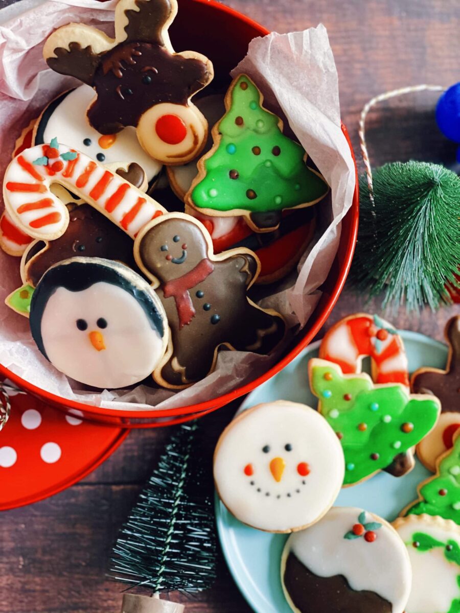 christmas icing cookies in a tin, a plate with more icing cookies