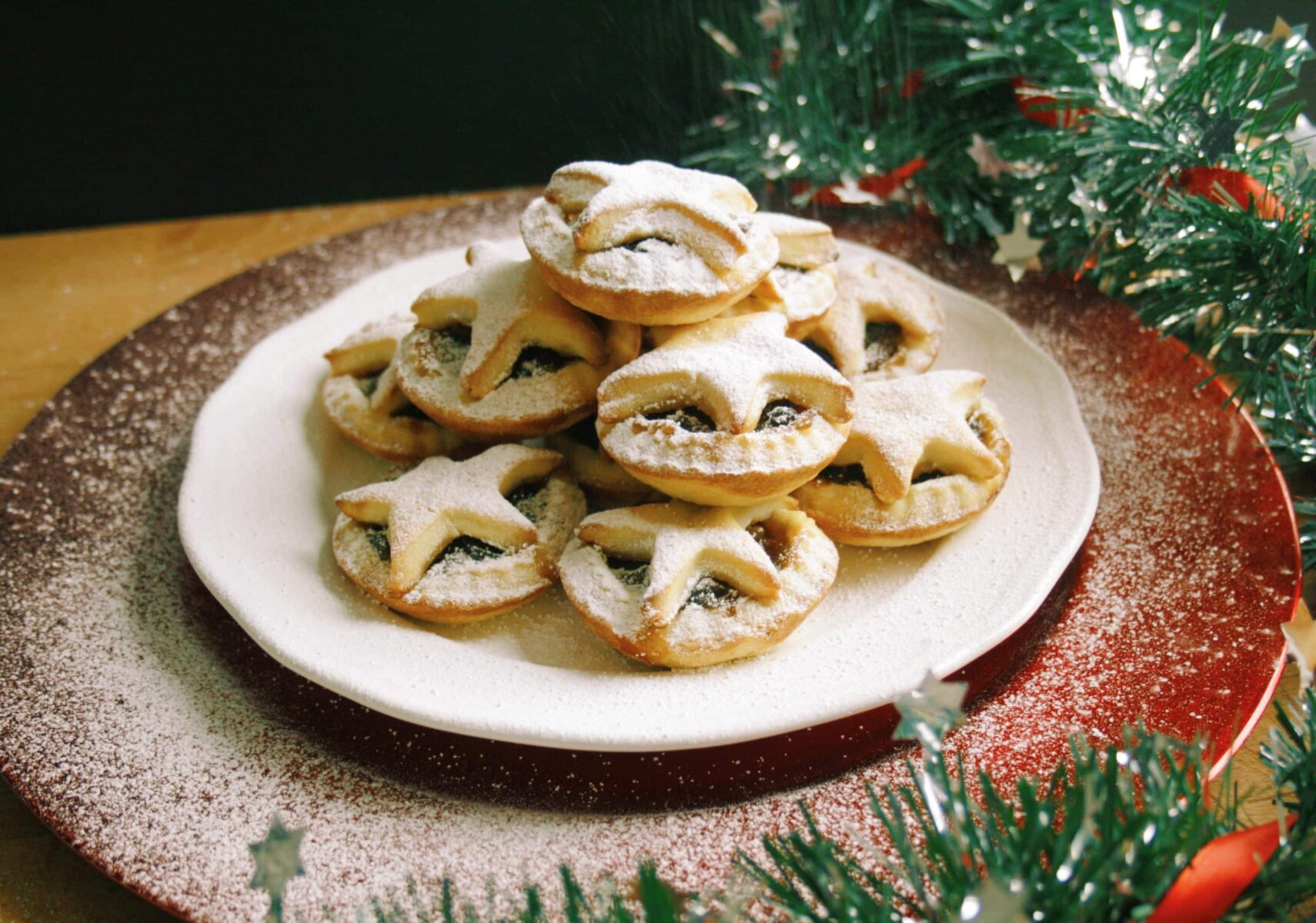 plate of mince pies, under a red plate and christmas garland on the side