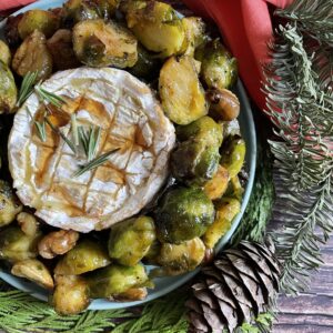 brussel sprouts wreath with camembert in the middle, a napkin, pines and wooden background