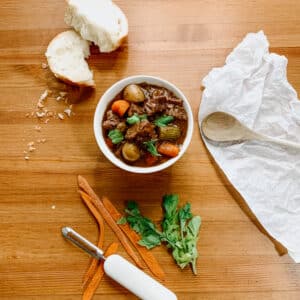 beef stew in a bowl, bread, carrots and parsley on the side, from above