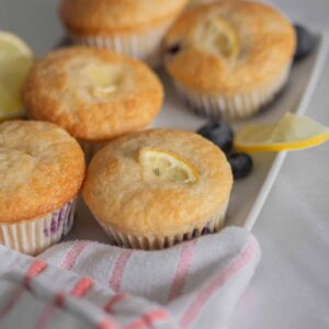 lemon blueberry muffin on a tray with more lemons and blueberries around , from the side