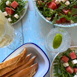 Watermelon and feta salad in three plates, bread, two glasses on the side