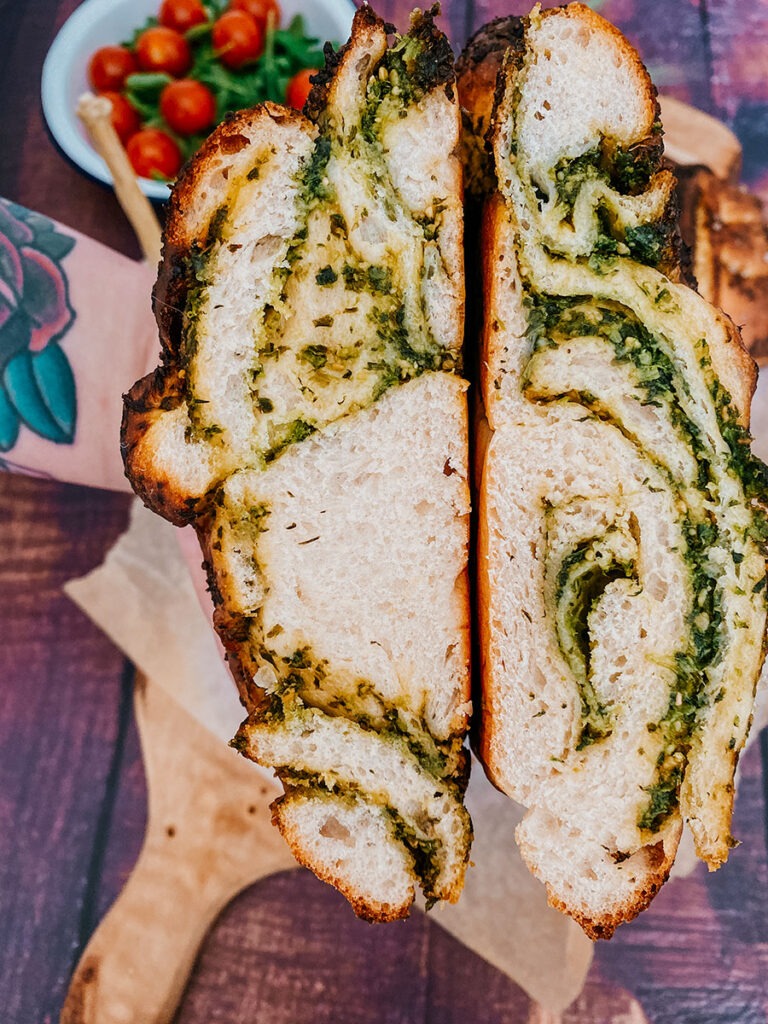 Wild Garlic Bread Braided with Homemade Pesto 6 close up of garlic loaf, garlic and tomatoes on the side, on a wooden background