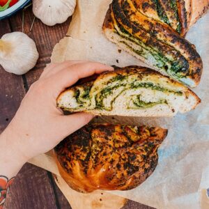 Wild Garlic Bread Braided with Homemade Pesto 4 close up of garlic loaf, garlic bread on, garlic and tomatoes on the side, on a wooden background