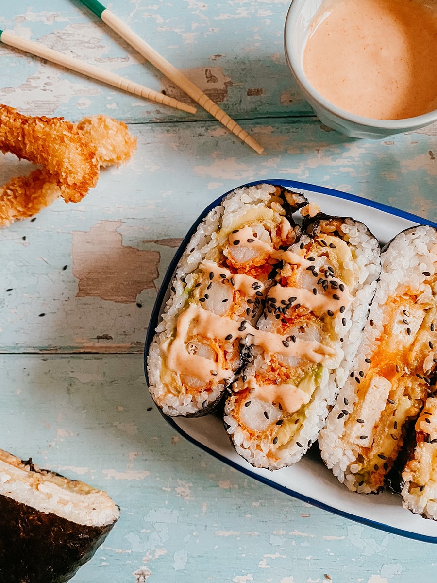 A white dish with two different onigirazu sandwiches, chopsticks and tempura prawns.