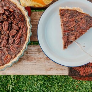 Chocolate Pecan Pie Recipe 4 pecan pie slice on a wooden slate and napkins, a pecan pie on the side