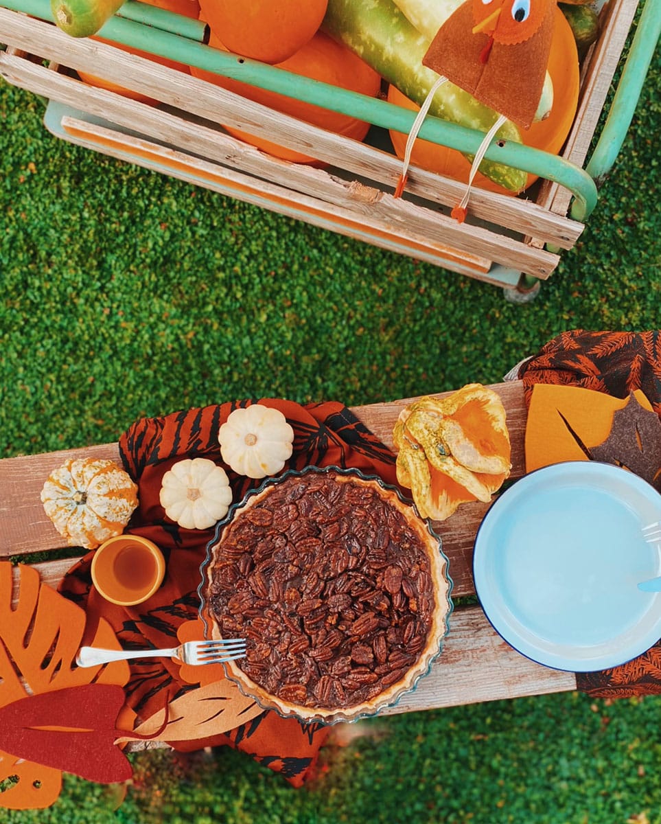 pecan pie slice on a wooden slate and napkins, a cart with pumpkins