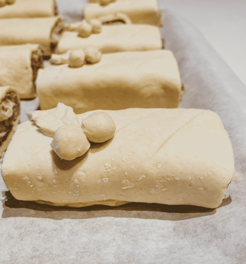 Christmas Sausage Rolls - Festive Appetizer Recipe 4 christmas sausage rolls on a baking tray before going in the oven