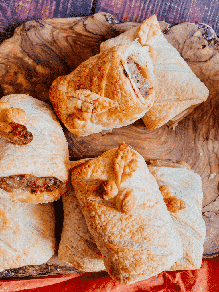 Christmas Sausage Rolls - Festive Appetizer Recipe 3 from top - christmas sausage rolls on a wooden board, over a red towel,
