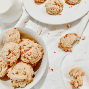 two plates of cookies, on a white napkin, glass of milk and more cookies broken on the side