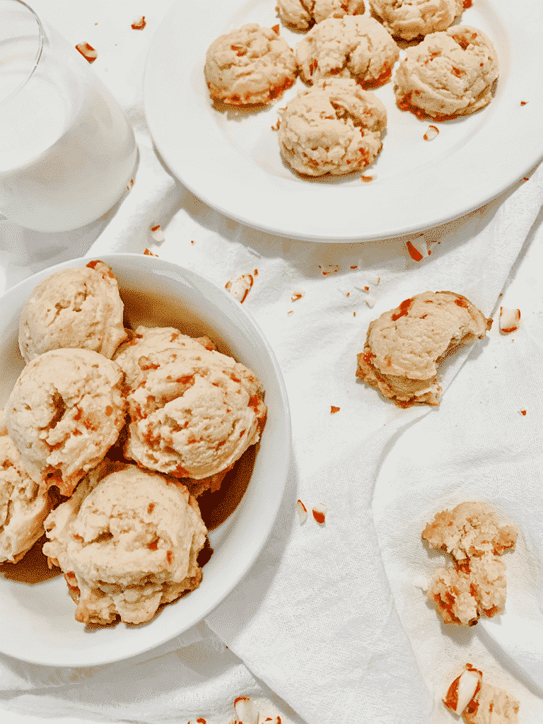 two plates of cookies, on a white napkin, glass of milk and more cookies broken on the side
