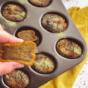 matcha mochi muffins in a tin on a yellow napkin, a hand squeezing a muffin, pin image