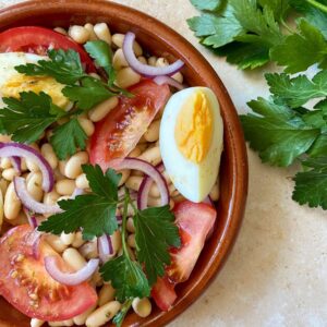 10 Minutes Summer Butter Beans Salad 2 close up, bean salad in a bowl with eggs and tomatoes, parsley on the background and a napkin