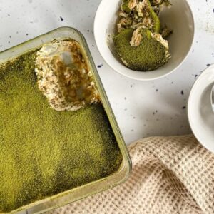 Matcha Tiramisu Easy Recipe 2 matcha tiramisu in a dish, plates with slices on the side and a napkin, from above