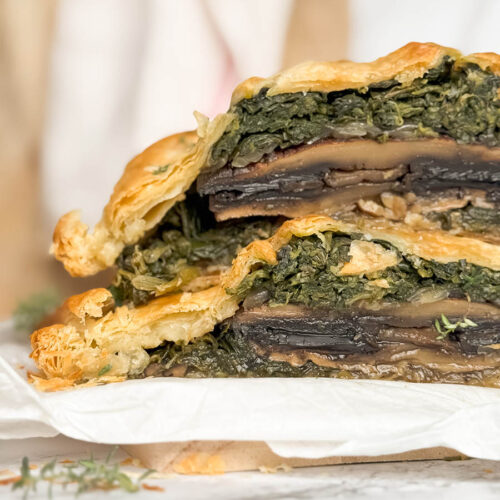 close up detail sliced vegan mushroom wellington from front, on parchment paper and wooden board