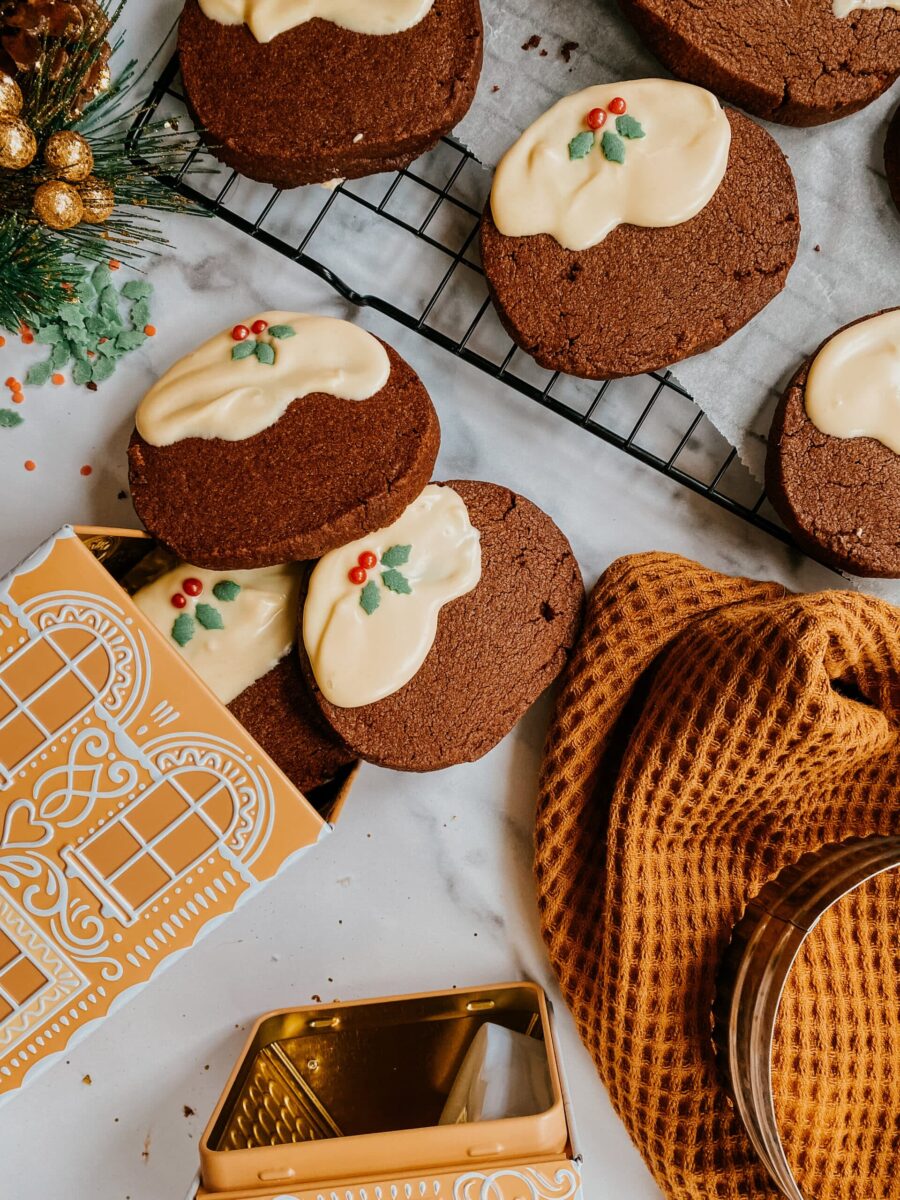 christmas pudding chocolate biscuits on a cookie rack and a napkin, two tin boxes on the side