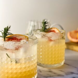 Amazing Sparkling Grapefruit Mocktail Recipe 4 grapefruit mocktails in two cocktail glasses, jug with more behind- close up