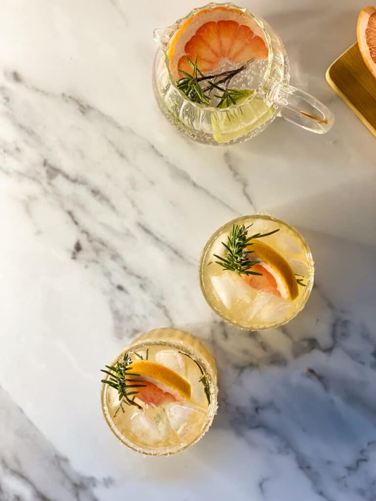 Amazing Sparkling Grapefruit Mocktail Recipe 5 two glasses containing a grapefruit mocktail with rosemary, on the back a grapefruit, from above