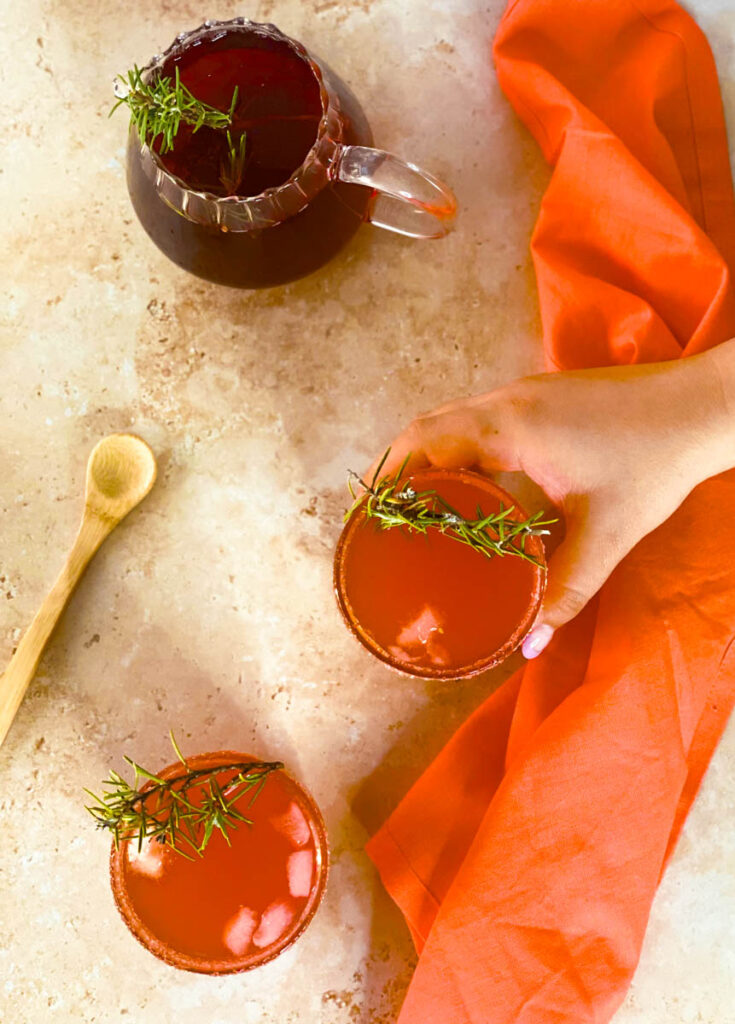 5 Minutes Love Potion Cocktail Recipe 4 from top, two glasses of love potion cocktail with rosemary as garnish, hand holding one