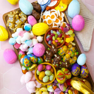 easter candy charcuterie board on a wooden board, selection of candies, napkin on the side