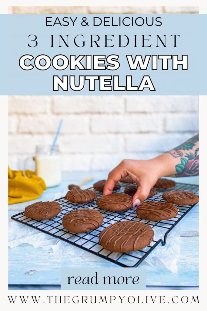 a hand grabbing a nutella cookie, on the background a white wall, a milk glass and a yellow napkin