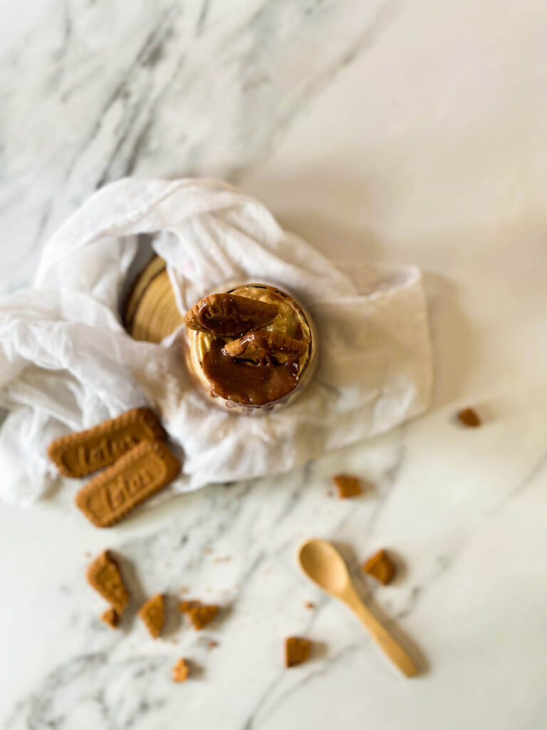 Deliciously Irresistible Biscoff Overnight Oats Recipe 5 the Biscoff overnight oats in a serving glass with garnish, on top of a white napkin and with lotus cookies around