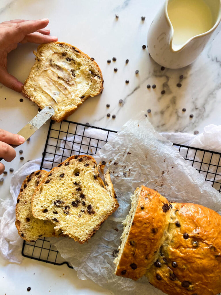 Delicious Fluffy Chocolate Chip Brioche Recipes 1 wire rack with chocolate chip brioche on, a hand putting butter on a slice, chocolate chips