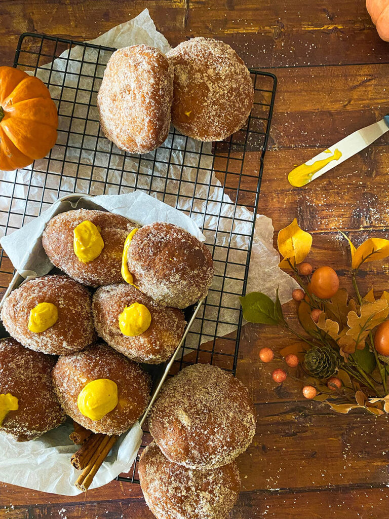 The Best Pumpkin Cheesecake Donuts: Perfect Fall Treat 5 pumpkin cheesecake donut recipe, donuts seen from above in a metal container over a cooling rack