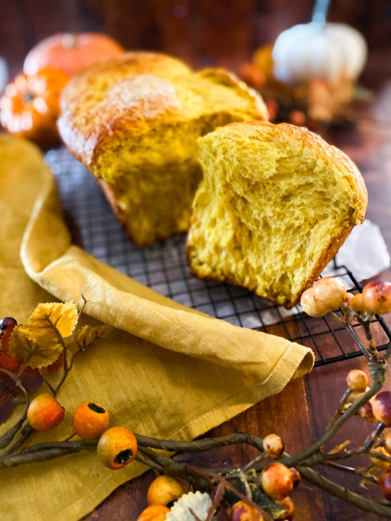 Easy Pumpkin Brioche Recipe - Fall Breakfast Staple 6 two pieces of pumpkin brioche on a yellow towel, on a wire rack, wood background