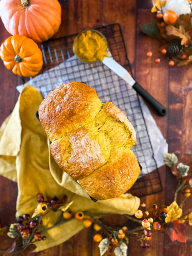 Easy Pumpkin Brioche Recipe - Fall Breakfast Staple 5 pumpkin brioche on a yellow towel, on a wire rack, wood background, from the top