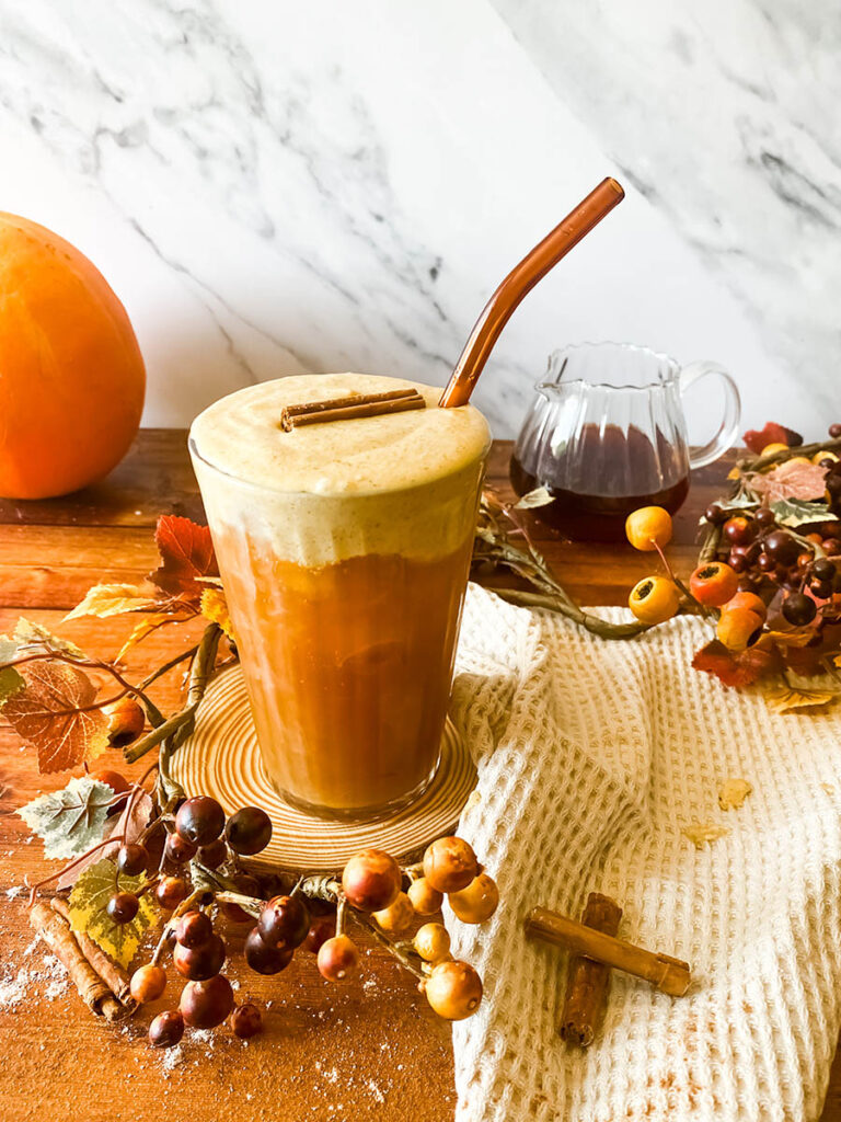 Ultimate Pumpkin Cold Foam Recipe, Starbucks Copycat 2 pumpkin cold foam recipe served over cold brew coffee with a brown glass straw and some elements recalling autumn all around