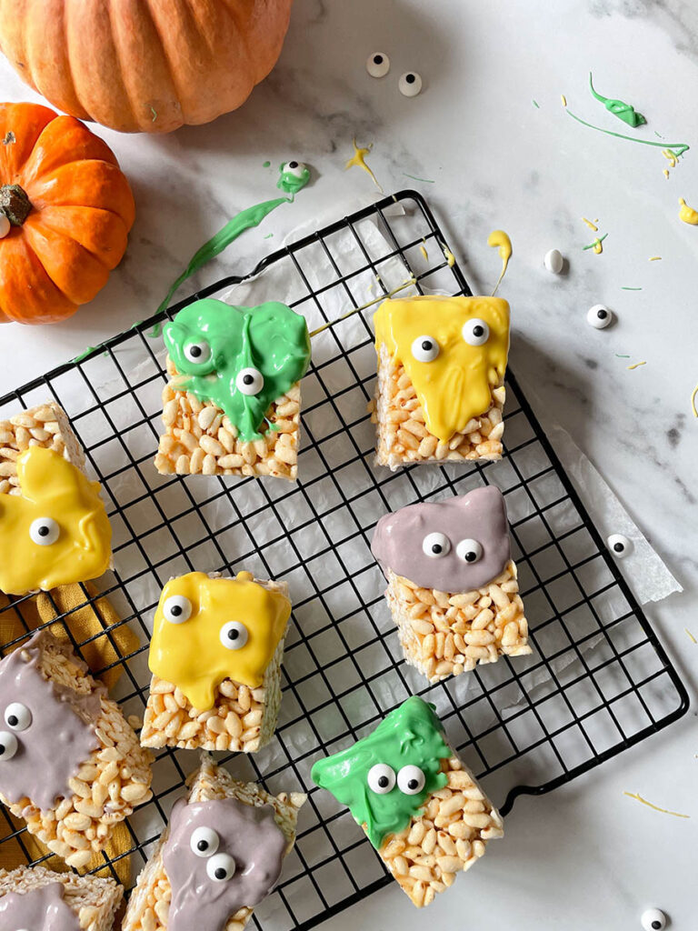 MM Rice Krispie Treats - The Delicious Monster Mash Treats 1 MM rice krispie treats on a cooling rack with pumpkins scattered around