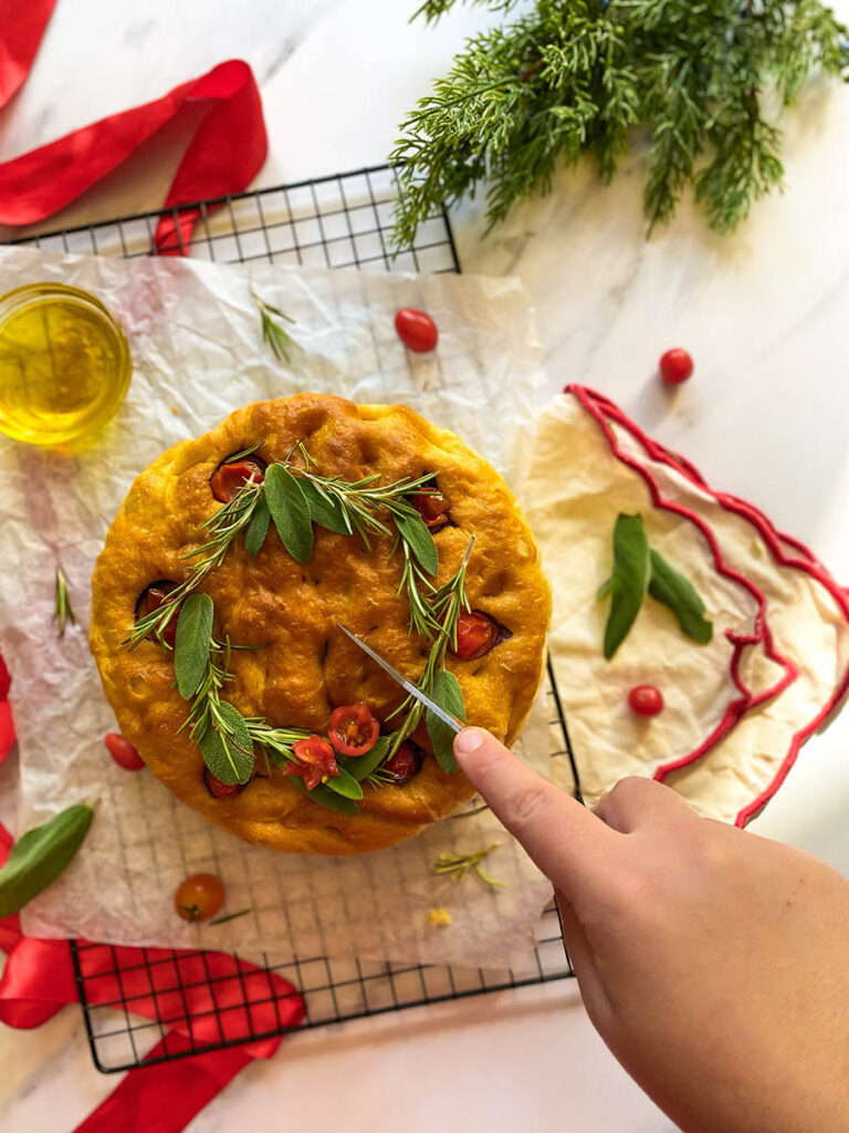 Christmas Focaccia: The Most Delicious Bread With A Festive Twist 4 Christmas focaccia on a cooling rack with tomatoes, rosemary and sage, over a red and white napkin