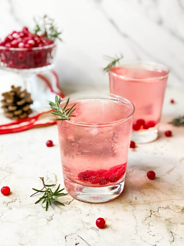 Super Mistletoe Kiss Cocktail Recipe for a Jolly Holiday Season 8 mistletoe kiss cocktail glasses with fresh rosemary and a red ribbon on the background