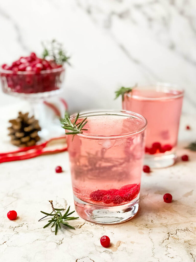 Super Mistletoe Kiss Cocktail Recipe for a Jolly Holiday Season 7 mistletoe kiss cocktail glasses with fresh rosemary and a red ribbon on the background