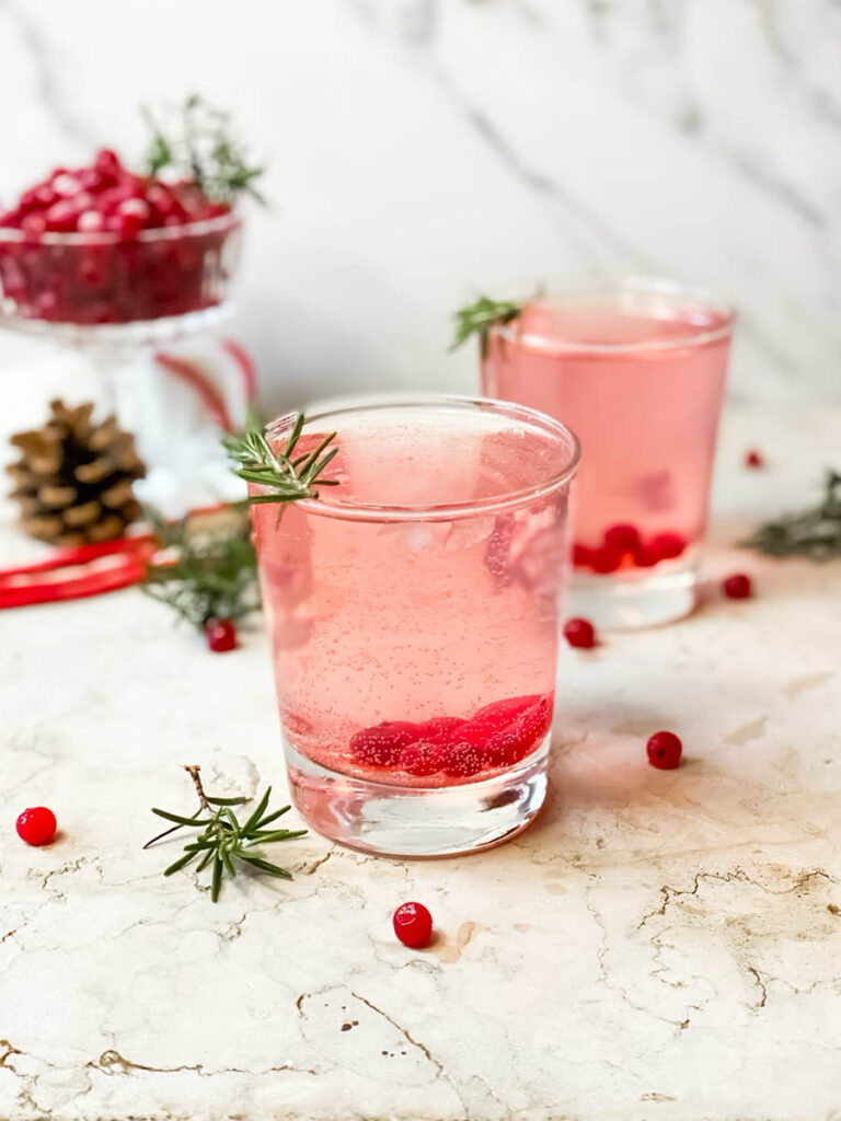 Super Mistletoe Kiss Cocktail Recipe for a Jolly Holiday Season 3 mistletoe kiss cocktail glasses with fresh rosemary and a red ribbon on the background