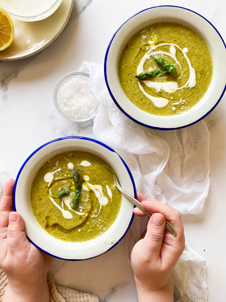 Broccoli Asparagus Soup: Delicious Lunch Idea 2 lemon, salt, two towels and two bowl of broccoli asparagus soup, two hands holding one of the bowls