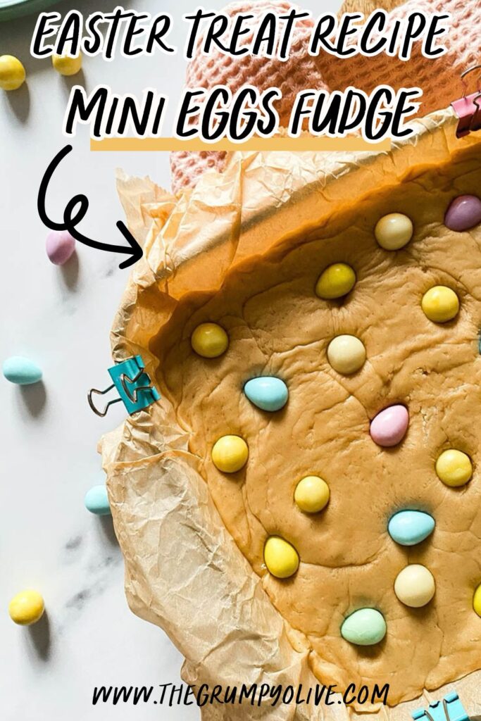 Easter Mini Eggs Fudge, Delicious And With No Condensed Milk 9 Mini eggs fudge in a tray over a pink napkin and with mini chocolate eggs scattered around the marble countertop