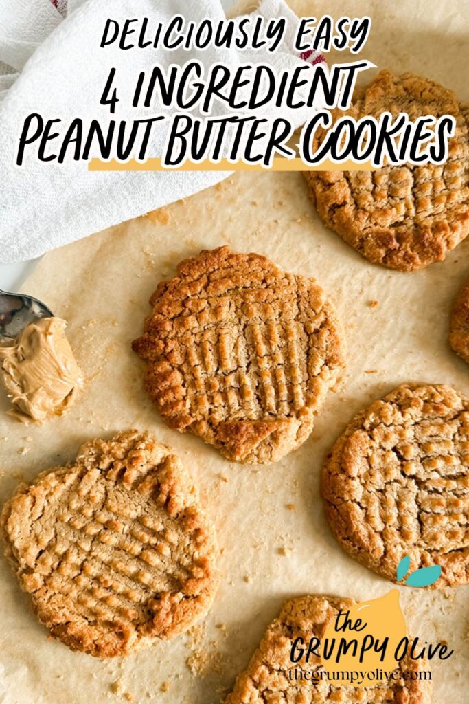 4 Ingredient Peanut Butter Cookies, Easy & Delicious Recipe 12 Freshly baked peanut butter cookies with a classic crisscross pattern sit on parchment paper. A spoonful of creamy peanut butter rests nearby, with a soft, white kitchen towel partially visible in the background.