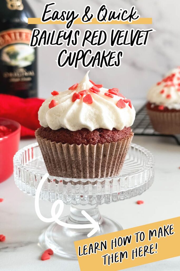 Baileys Red Velvet Cupcakes, The Perfect Valentine's Dessert 12 A red velvet cupcake with white frosting and red heart sprinkles, styled on a glass stand with bold text overlay that reads "Easy & Quick Baileys Red Velvet Cupcakes" and "Learn how to make them here!"