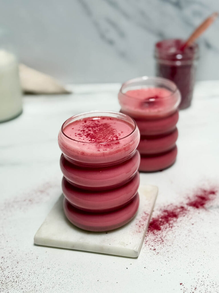 Red Latte Recipe, One Perfect For Valentine's Or Any Other Day Really 9 A vibrant red latte in focus, paired with another latte in the background. The marble coaster and powdery texture on the table add to the elegant, modern presentation.