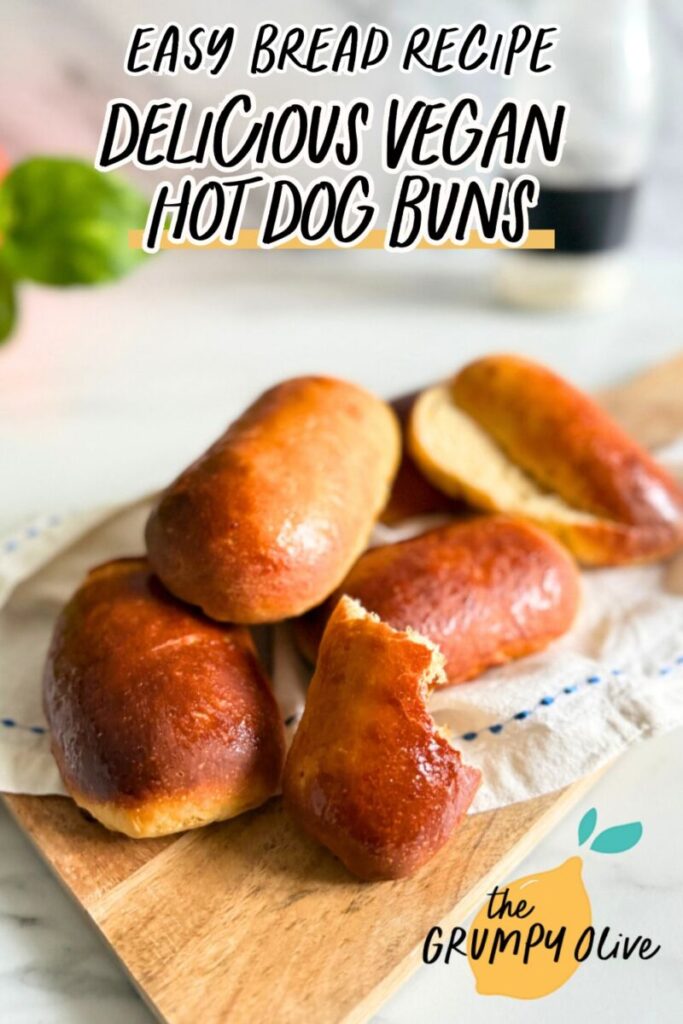 pin image - vegan hot dog buns on a towel on a wooden board, a bottle of flour and plant behind, on a marble background