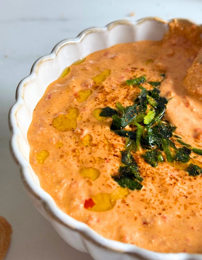 close up of paprika dip in a bowl with parsley on top and olive oil