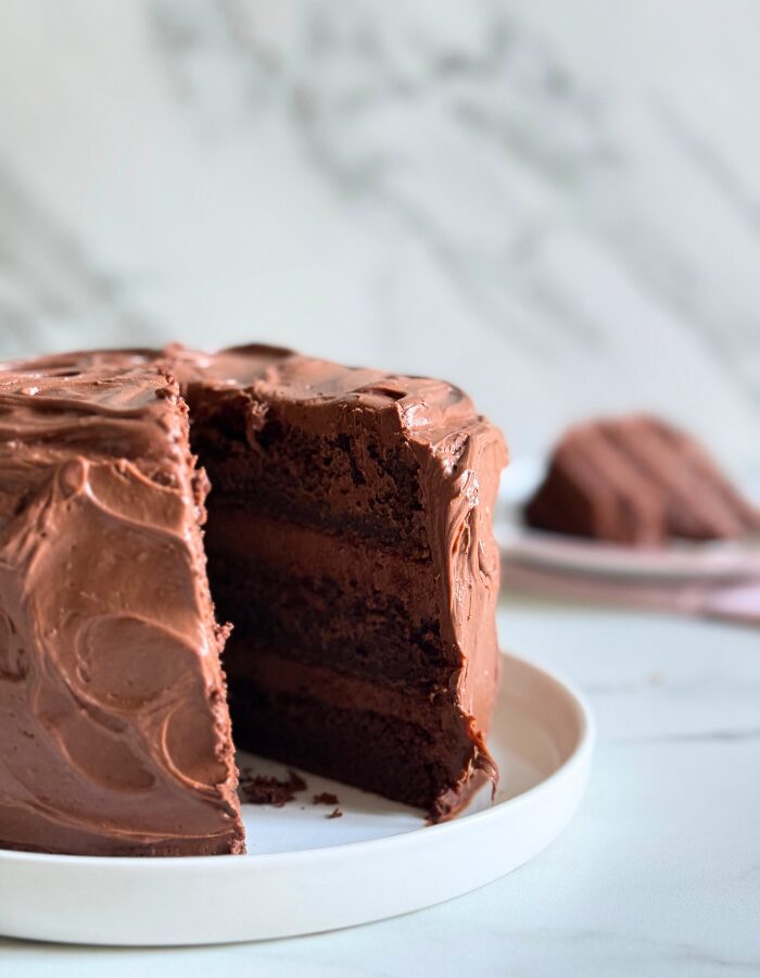 matilda's cake on a plate, a slice in the background, on a marble background
