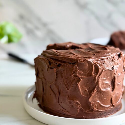 matilda's cake on a plate, a slice in the background, plant, on a marble background