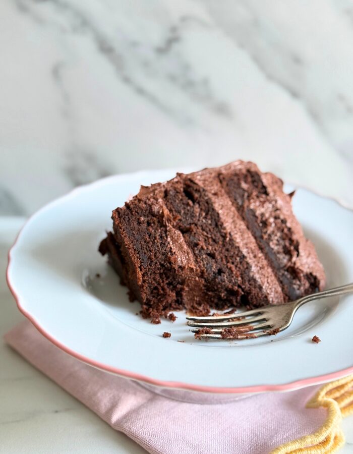 close up of a slice of matildas cake on a plate with a fork, on a pink towel