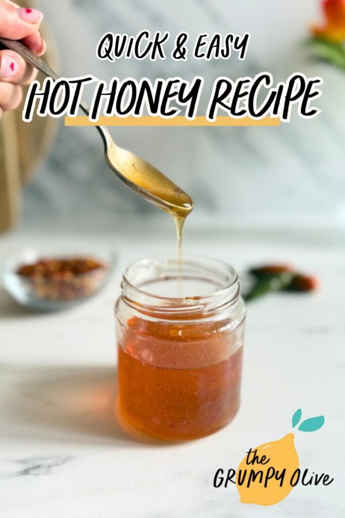 Easy Hot Honey Recipe - Quick Homemade Sauce 10 pin image - hot honey recipe in a jar, hand holding a spoon with some of it, behind a bowl with chilli flakes and green chilli peppers, on a marble background