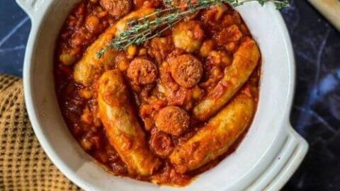 sausage and chorizo casserole with a napkin and spoon on the side, on a blue background